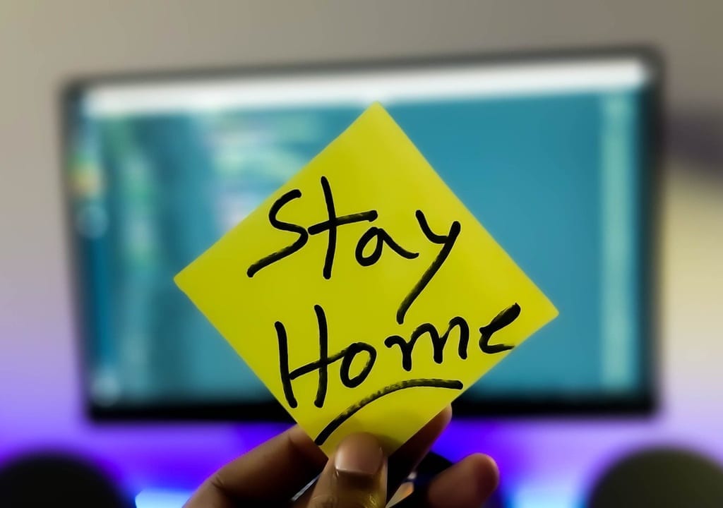 「Stay Home」と書かれた紙を持つ手