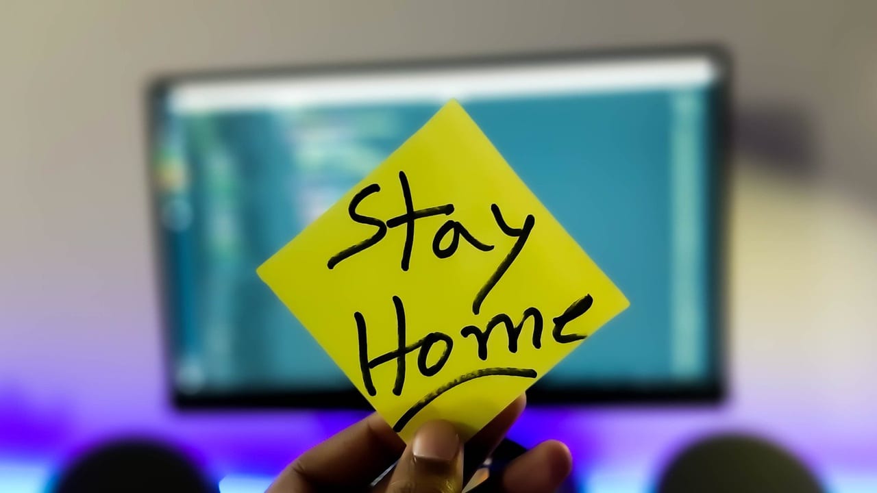 「Stay Home」と書かれた紙を持つ手