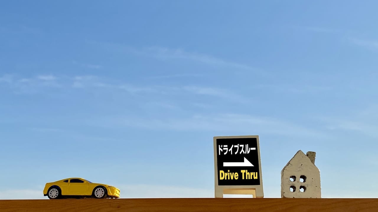 「ドライブスルー」と書かれた看板と車と建物