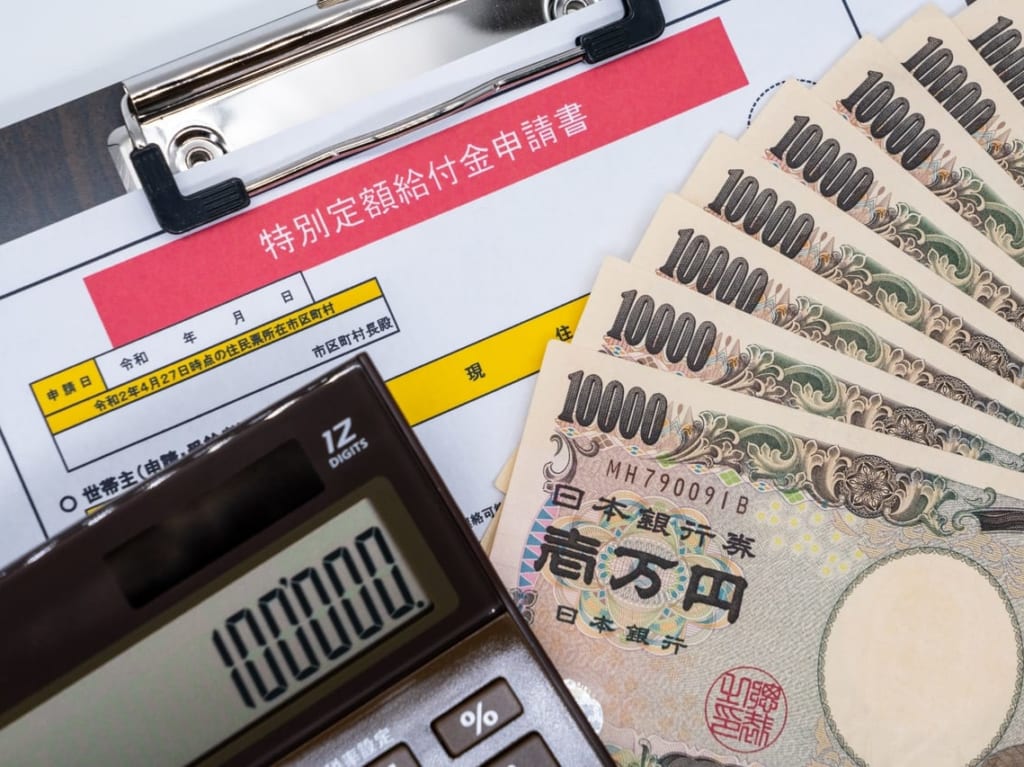 特別定額給付金の申請書類と1万円札と電卓