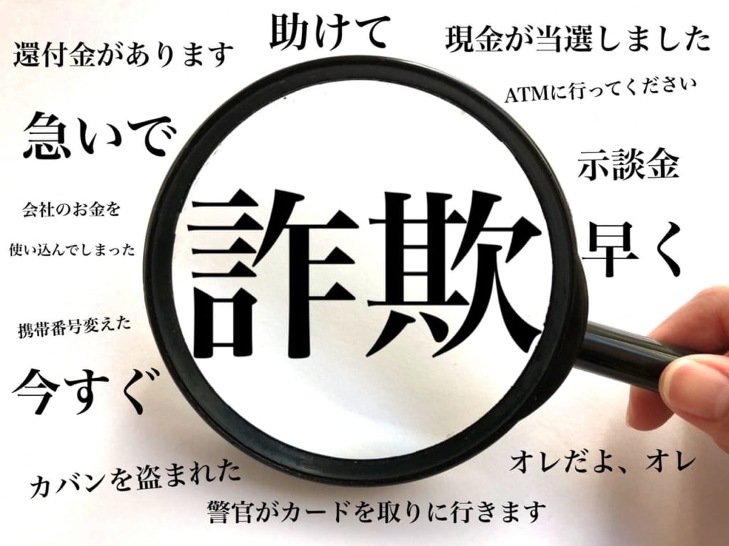 「詐欺」という文字と虫メガネを持つ人の手