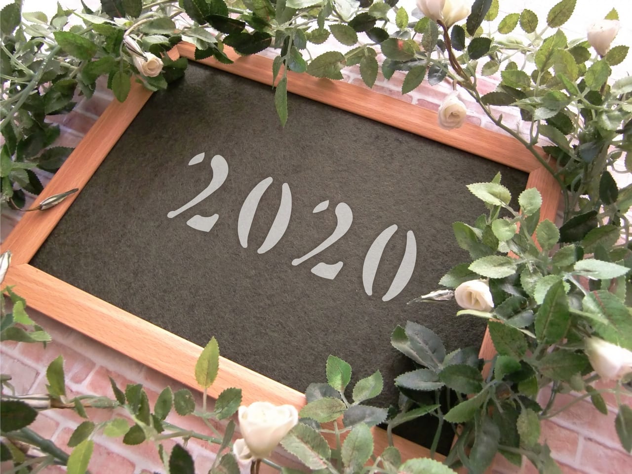 「2020」と書かれた黒板とバラの花