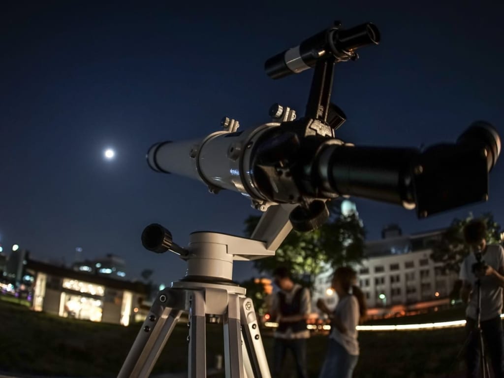 天体望遠鏡で夜空を観測する人たち