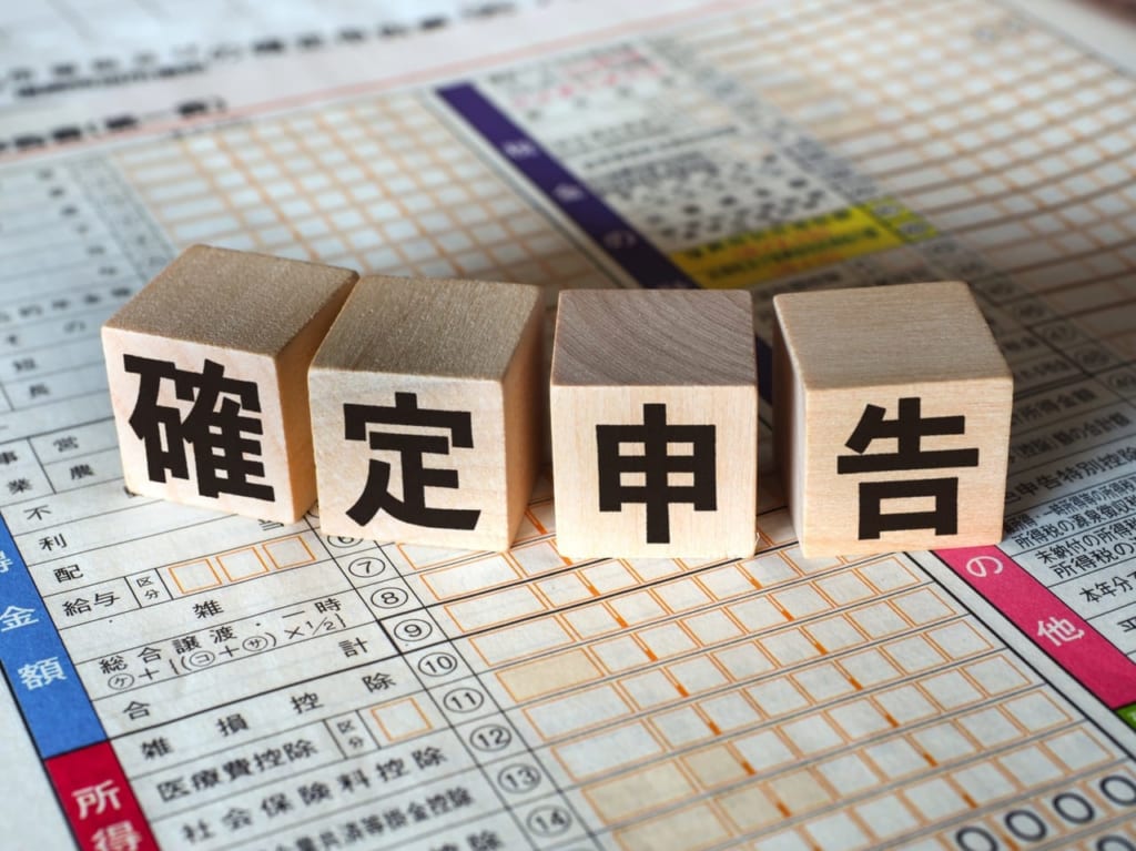 「確定申告」と書かれた木製のキューブと申告書類