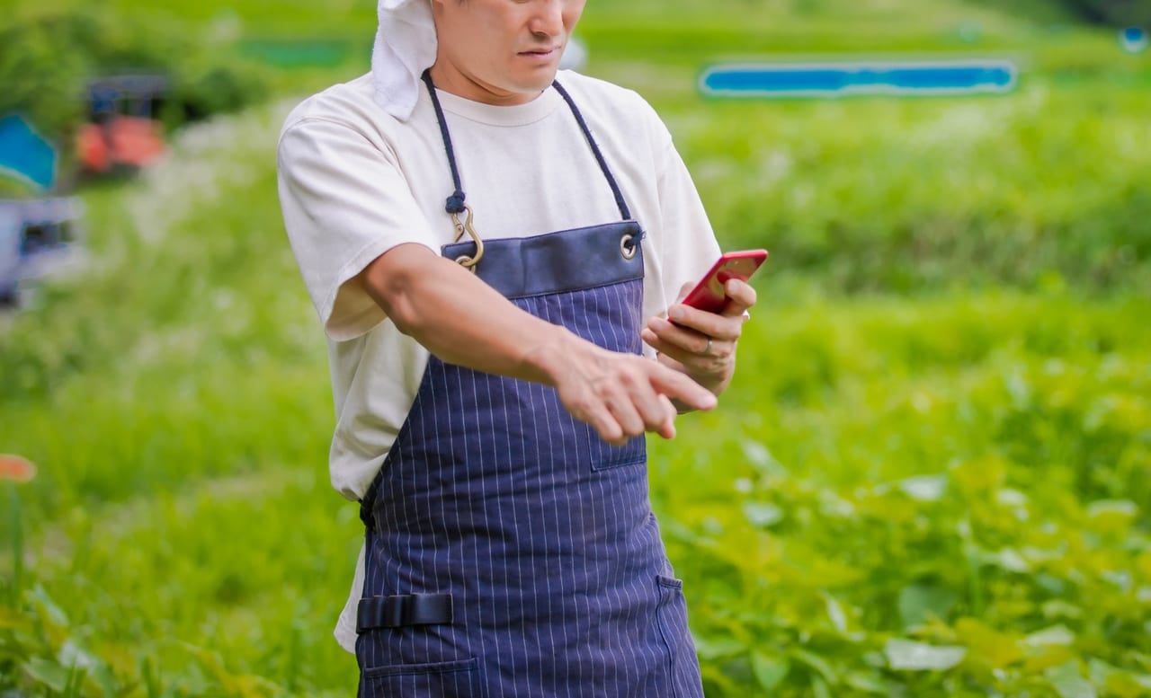 スマートフォンで農業を行う男性