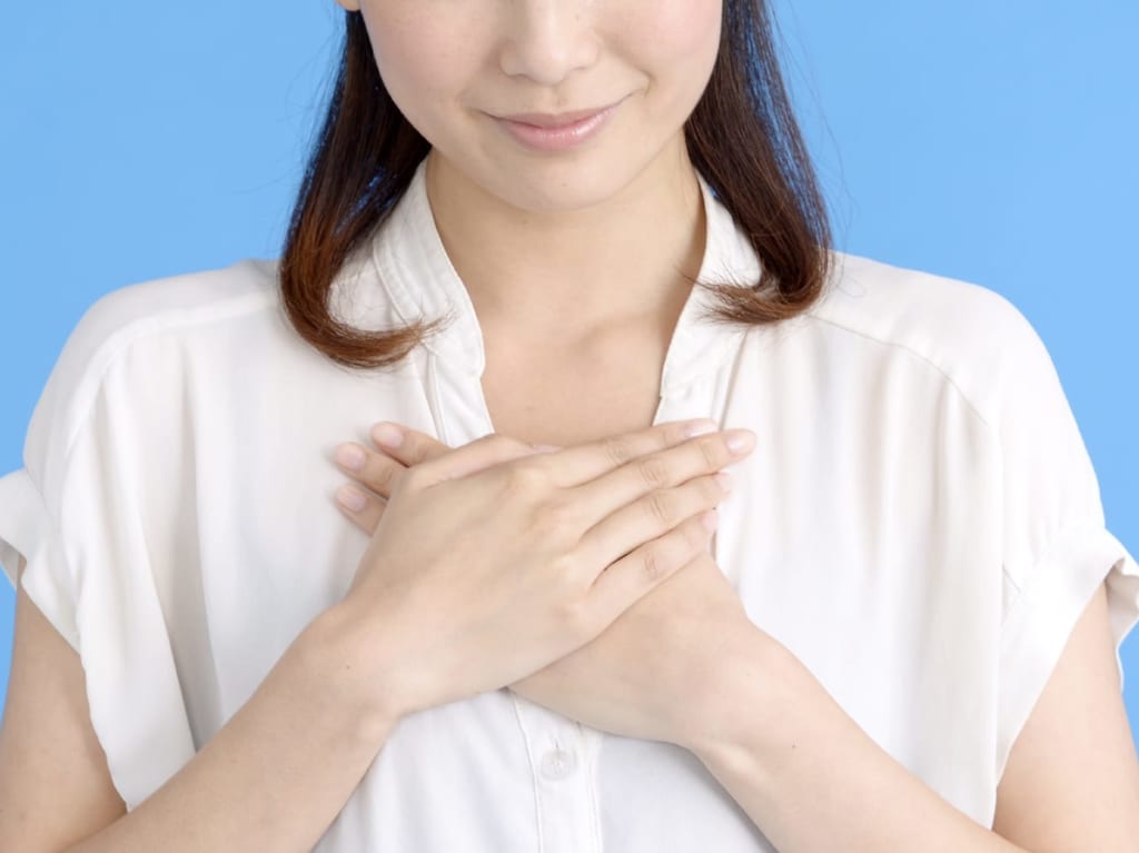 胸に手を当てて微笑みを浮かべる女性